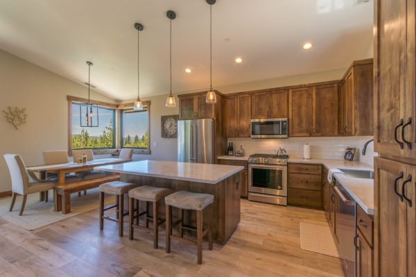 Inline image showing a newly constructed kitchen in Truckee, CA with hardwood floors, custom cabinets, eat in bar and pendant lighting. By WhiteFace Builders.